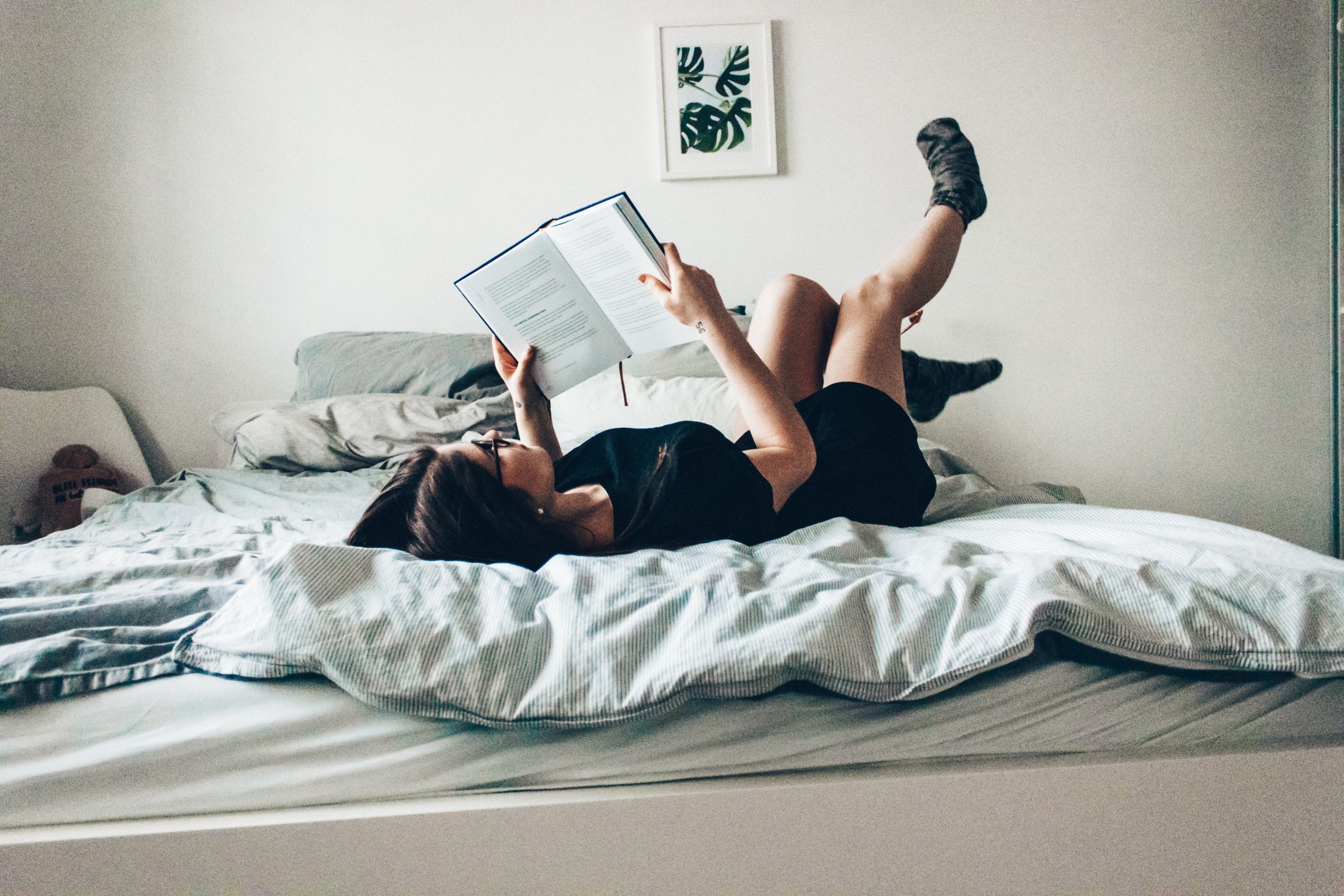 image of a woman reading a book on a bed